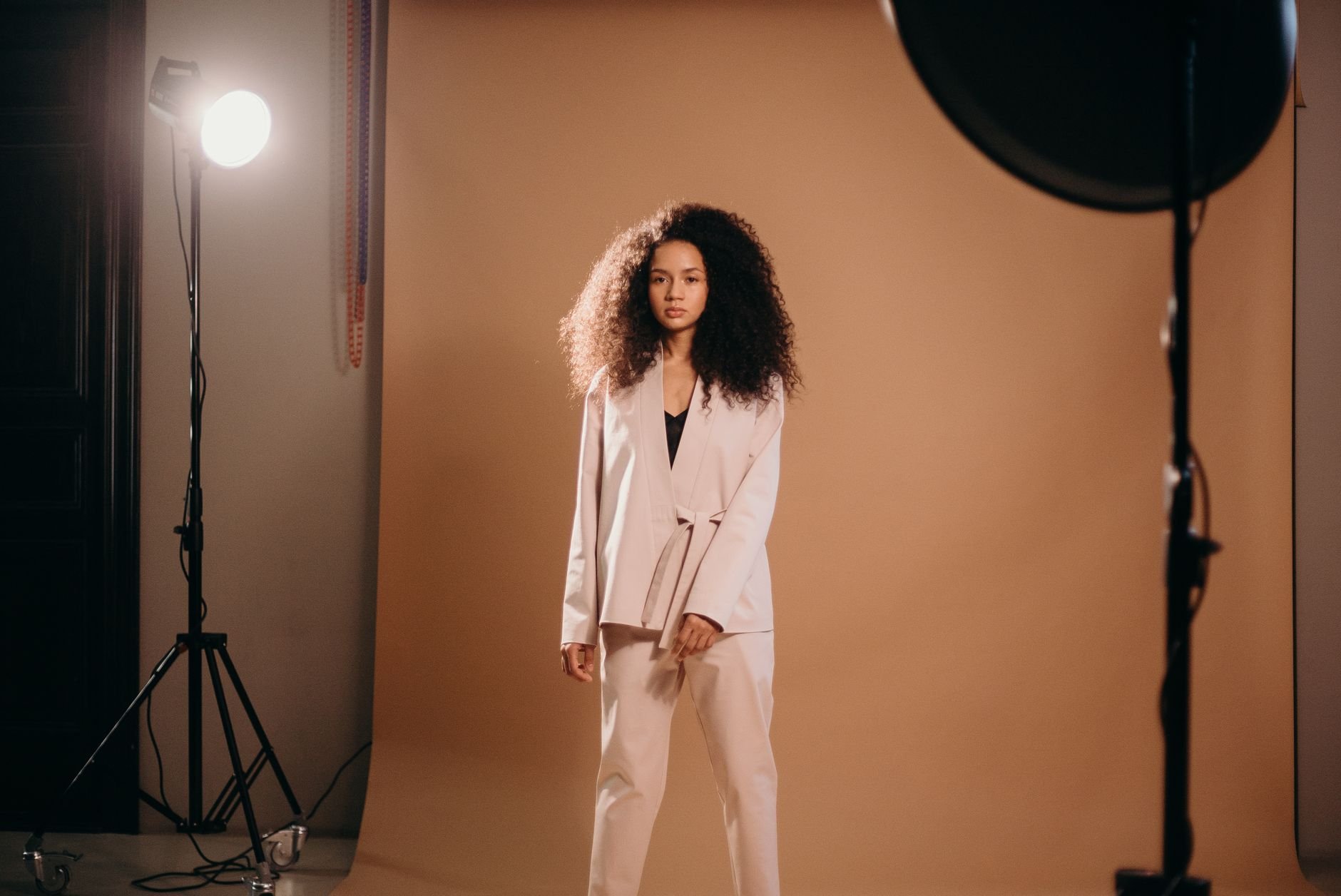 Elegant woman with afro hair posing in a professional studio setup.